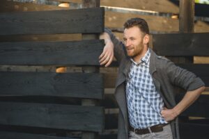 Portrait of young fashionable man against wooden fence