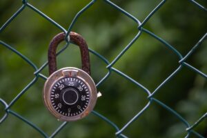 Closeup shot of a rusty lock hanging from a wired fence